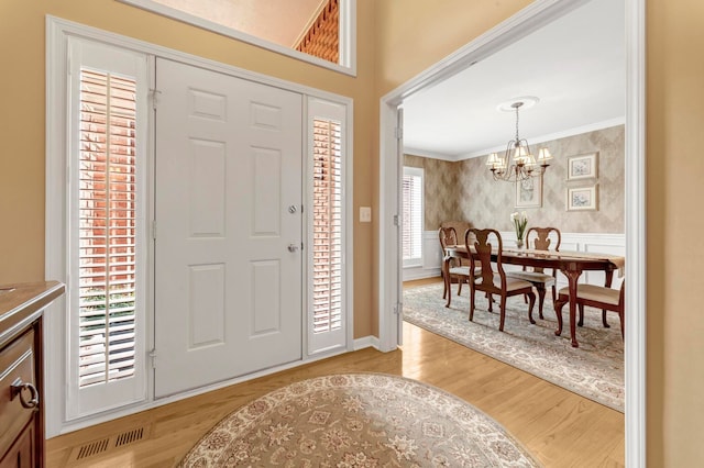 28022 Ashland Ave, Harrison Township, MI 48045 - entrance foyer featuring a chandelier, crown molding, light wood-type flooring, wallpapered walls, and wainscoting