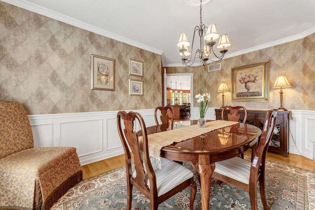 28022 Ashland Ave, Harrison Township, MI 48045 - dining area featuring a chandelier, light wood-style floors, a decorative wall, ornamental molding, and wainscoting