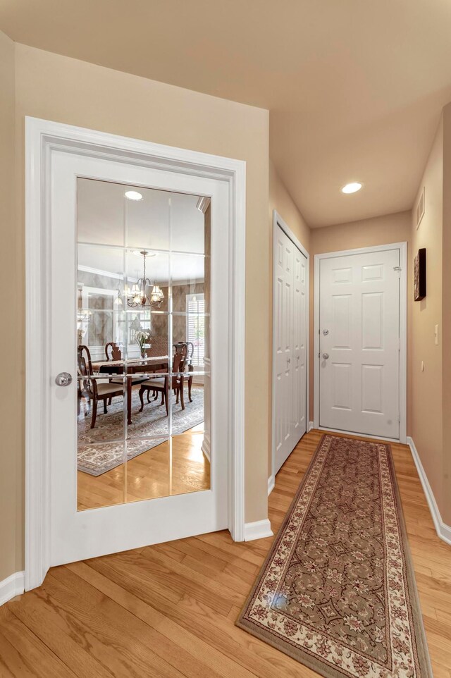28022 Ashland Ave, Harrison Township, MI 48045 - doorway to outside with light wood-type flooring, a chandelier, and baseboards