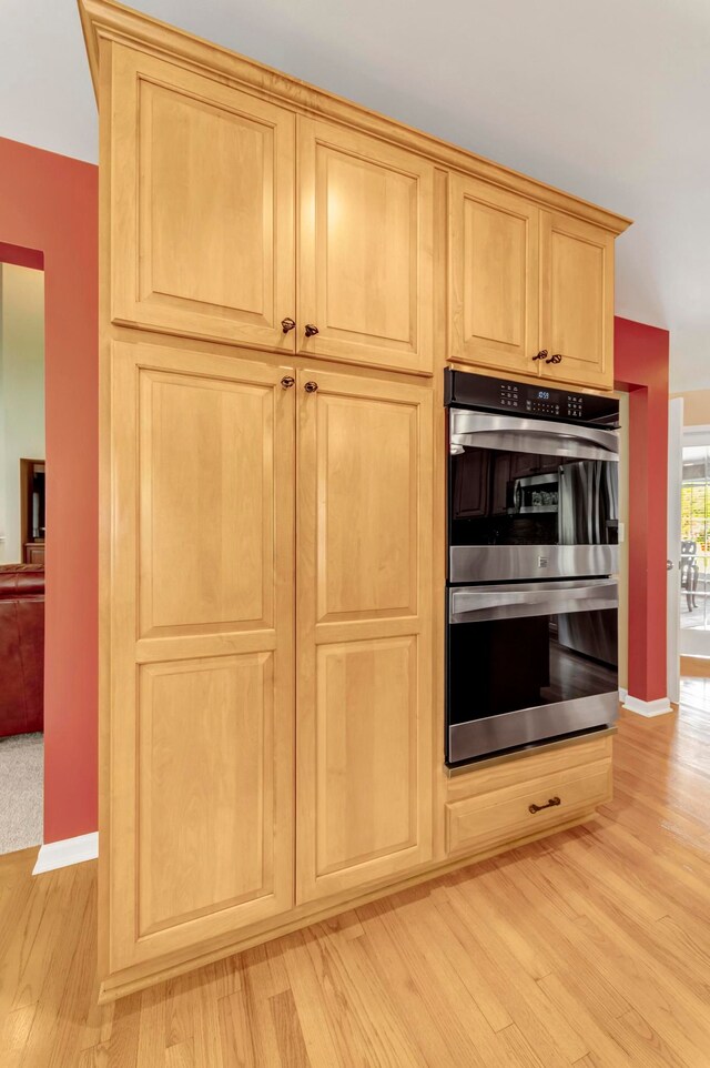 28022 Ashland Ave, Harrison Township, MI 48045 - kitchen featuring stainless steel double oven, light brown cabinets, light wood-style floors, and baseboards