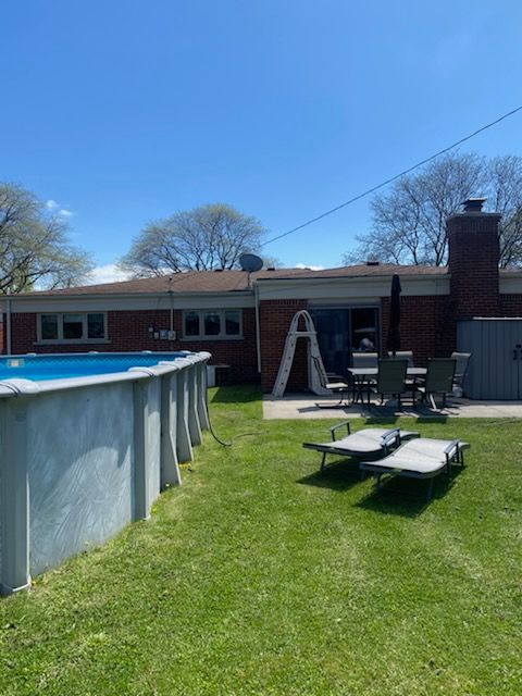 back of house with brick siding, an outdoor pool, a yard, and a patio