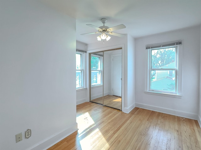unfurnished bedroom with baseboards, light wood-type flooring, a closet, and a ceiling fan