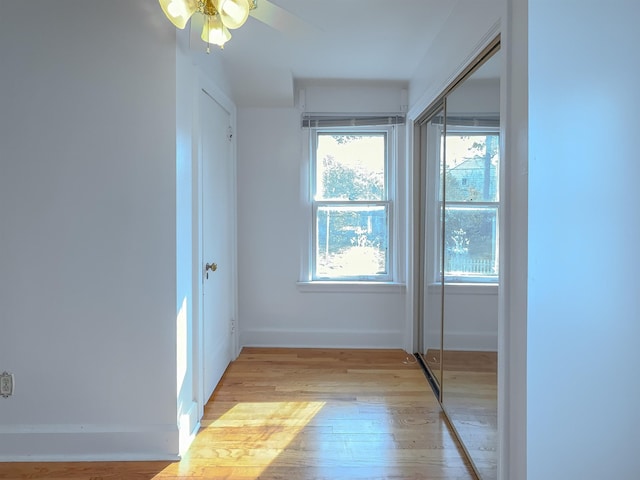 unfurnished bedroom featuring baseboards, light wood finished floors, and a closet