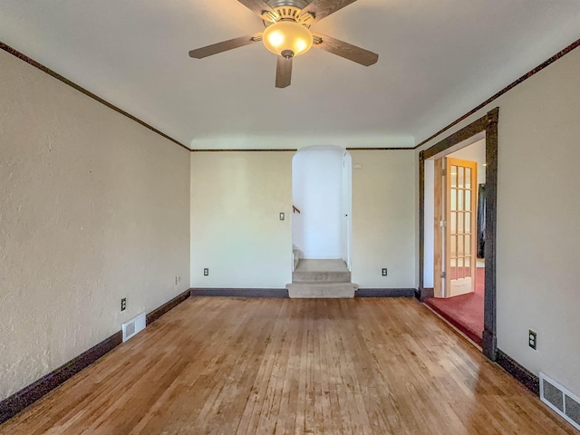 empty room with hardwood / wood-style floors, stairway, a ceiling fan, and baseboards