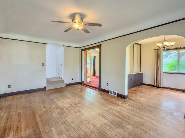 empty room featuring a chandelier, wood finished floors, arched walkways, a ceiling fan, and crown molding