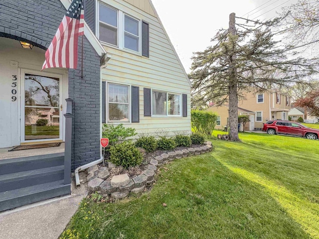 view of side of property featuring a lawn and brick siding