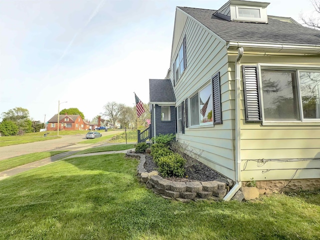 view of side of property with a yard and roof with shingles