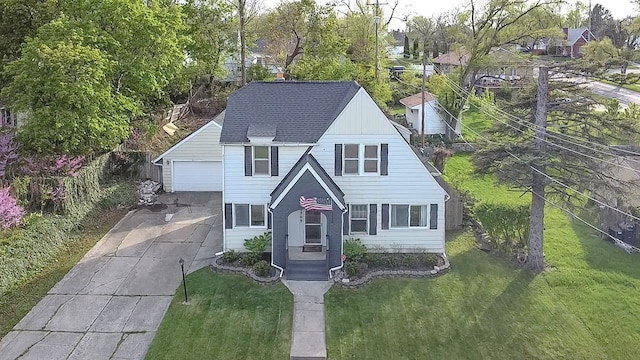 english style home featuring a front yard, a detached garage, and a shingled roof