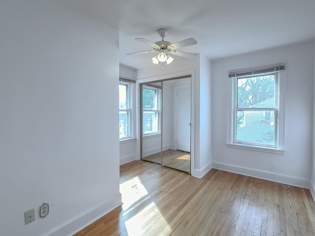 unfurnished bedroom featuring baseboards, a closet, light wood-type flooring, and ceiling fan