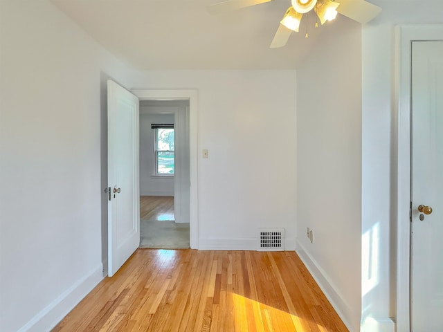 unfurnished room with light wood-style flooring, a ceiling fan, and baseboards