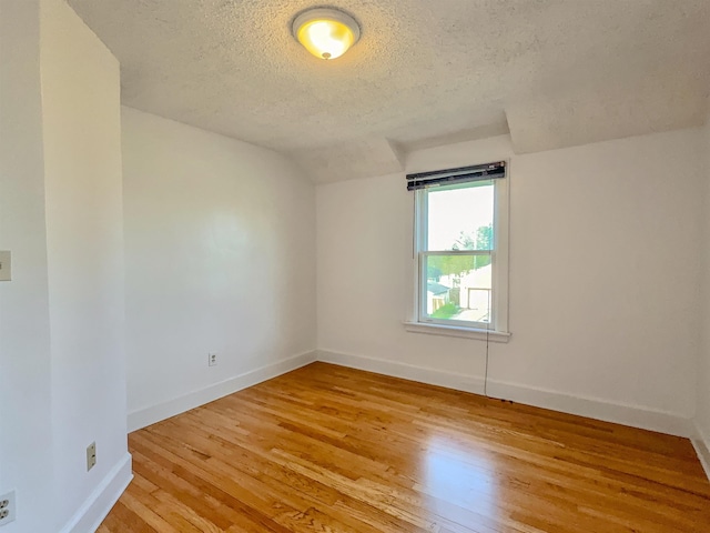 unfurnished room featuring a textured ceiling, light wood-style floors, and baseboards