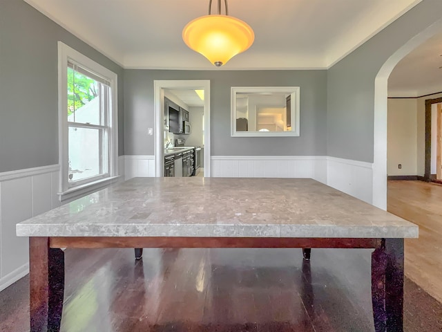 unfurnished dining area featuring wainscoting and arched walkways