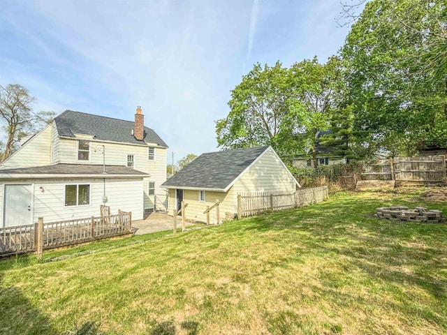 rear view of house with a chimney, an outdoor fire pit, an outbuilding, and a patio