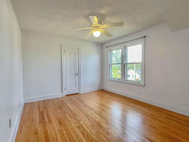spare room with light wood finished floors, a textured ceiling, baseboards, and a ceiling fan