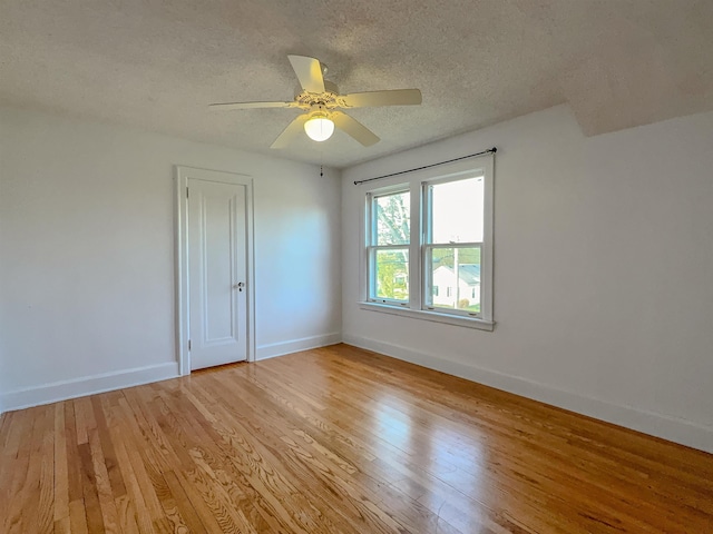 spare room with light wood finished floors, a textured ceiling, baseboards, and ceiling fan