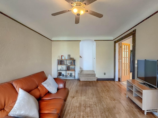 living area with wood finished floors, ceiling fan, and arched walkways