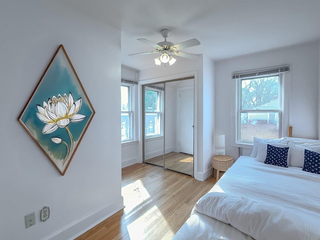 bedroom featuring baseboards, a closet, light wood finished floors, and ceiling fan