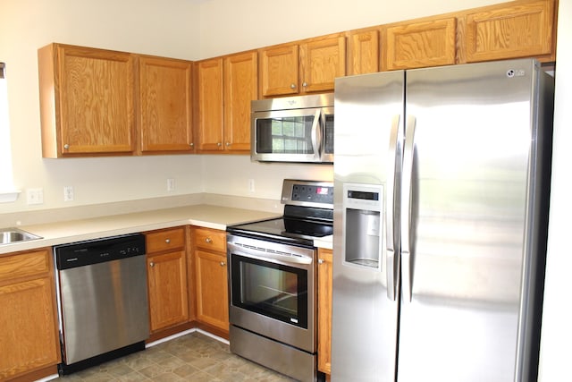 9541 Lakeside Dr, Ypsilanti, MI 48197 - kitchen with appliances with stainless steel finishes, light countertops, a sink, and brown cabinetry