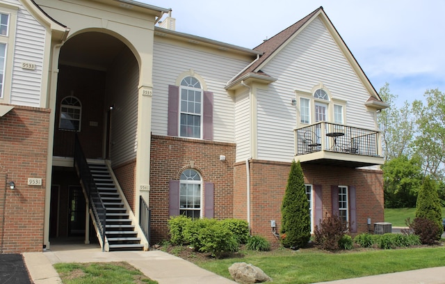 9541 Lakeside Dr, Ypsilanti, MI 48197 - view of front facade featuring a balcony, stairs, central AC, and brick siding