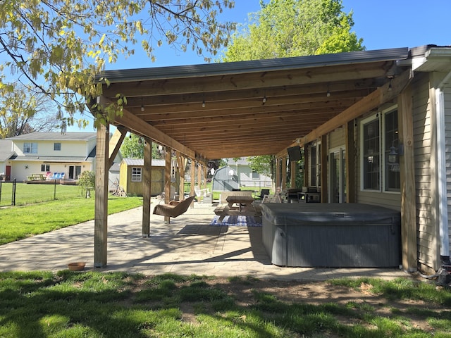 view of community featuring a shed, a hot tub, an outbuilding, and a patio
