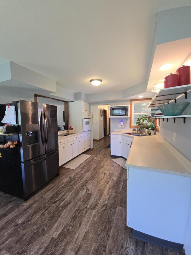 kitchen featuring stainless steel fridge with ice dispenser, white oven, black microwave, white cabinets, and dark wood-type flooring