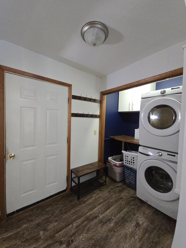 clothes washing area featuring stacked washing machine and dryer and dark wood-style floors