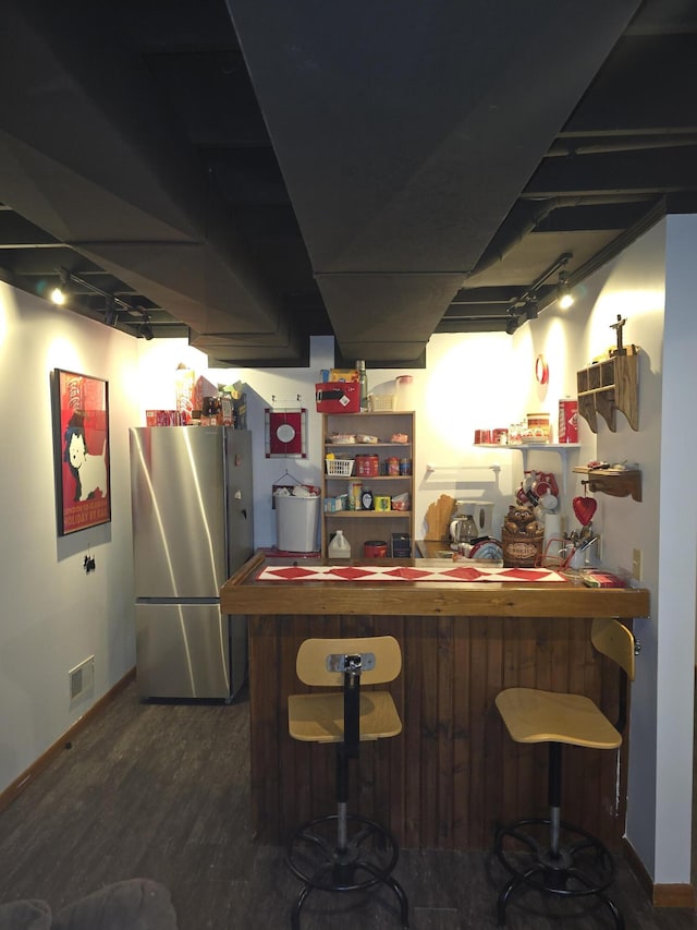 indoor bar featuring freestanding refrigerator, wood finished floors, and baseboards