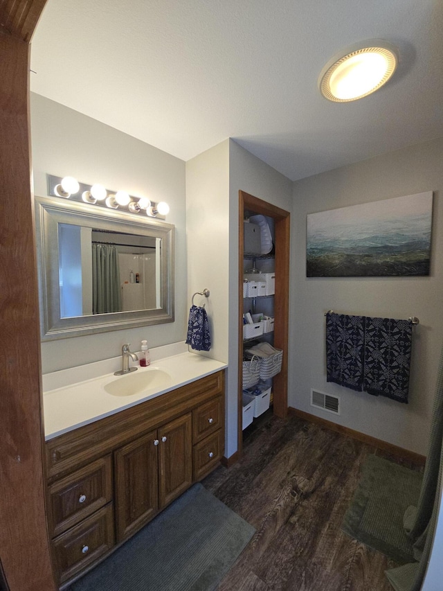 full bathroom with wood finished floors, vanity, a shower with curtain, and baseboards