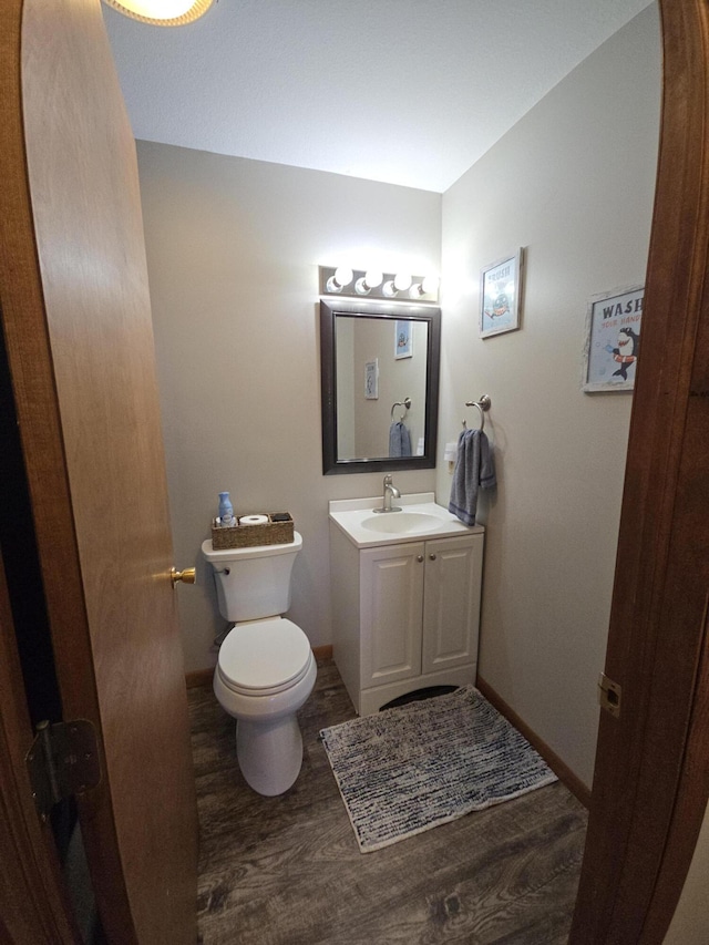 bathroom featuring wood finished floors, toilet, vanity, and baseboards