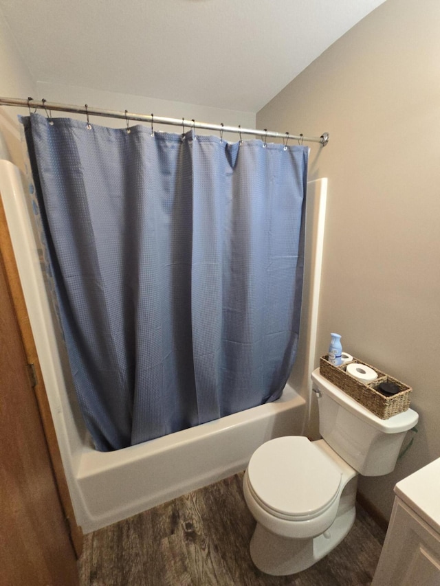bathroom featuring wood finished floors, shower / bath combo with shower curtain, toilet, and vanity