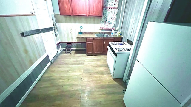 13646 Ryan Rd, Hamtramck, MI 48212 - kitchen with white appliances, light wood-type flooring, reddish brown cabinets, a sink, and baseboards
