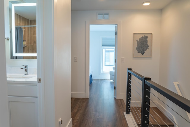 138 Gillis St, Traverse City, MI 49684 - hallway featuring a sink, dark wood-style flooring, baseboards, and an upstairs landing