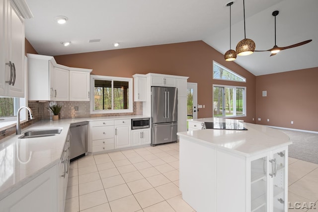 kitchen with appliances with stainless steel finishes, a sink, a center island, decorative backsplash, and high vaulted ceiling