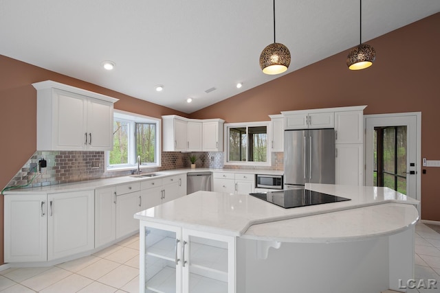 kitchen featuring stainless steel appliances, a sink, vaulted ceiling, decorative backsplash, and light tile patterned floors