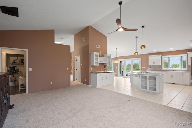 kitchen featuring ceiling fan, light colored carpet, glass insert cabinets, white cabinets, and high vaulted ceiling