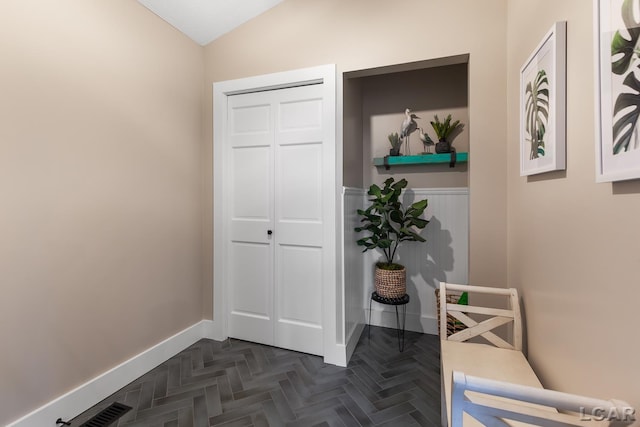 hallway featuring lofted ceiling and baseboards