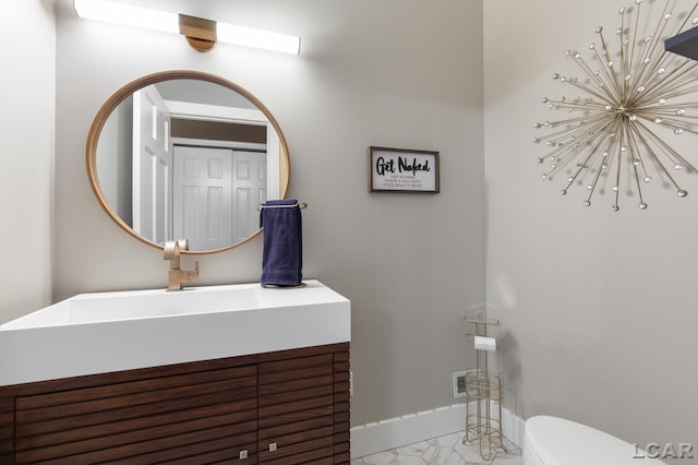 bathroom featuring toilet, vanity, and baseboards