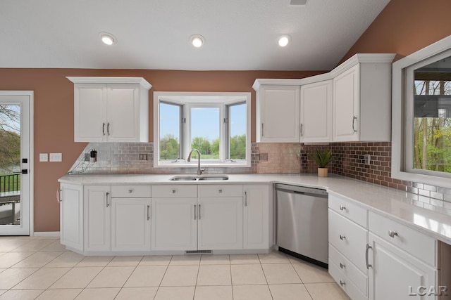 kitchen featuring dishwasher, a sink, healthy amount of natural light, tasteful backsplash, and vaulted ceiling