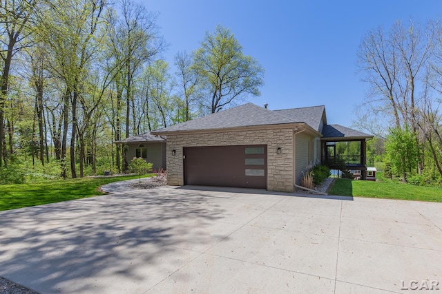 view of property exterior featuring stone siding, driveway, an attached garage, a yard, and roof with shingles