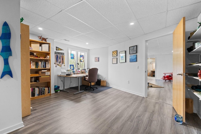 office space with a paneled ceiling, wood finished floors, baseboards, and recessed lighting