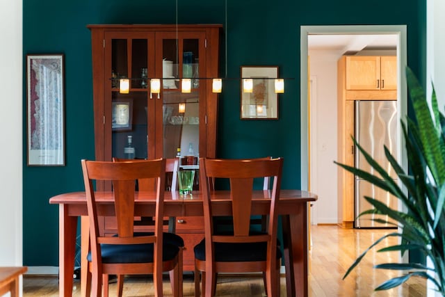 dining space featuring light wood-style flooring and baseboards