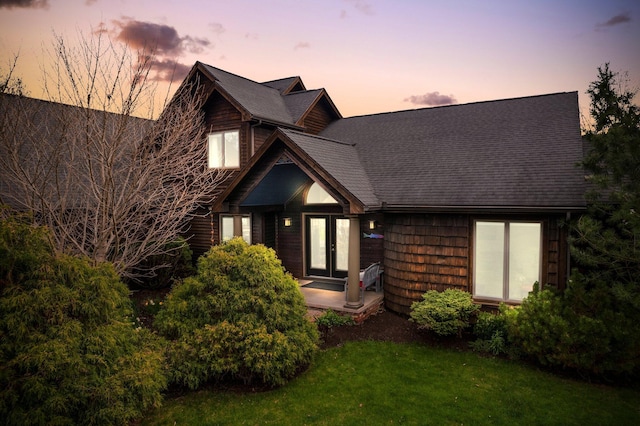 view of front of home featuring french doors, a front lawn, and roof with shingles