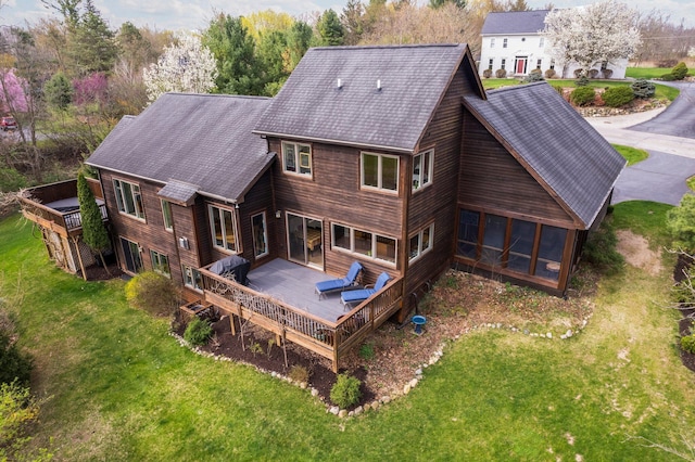 rear view of house featuring a wooden deck, a yard, and a sunroom