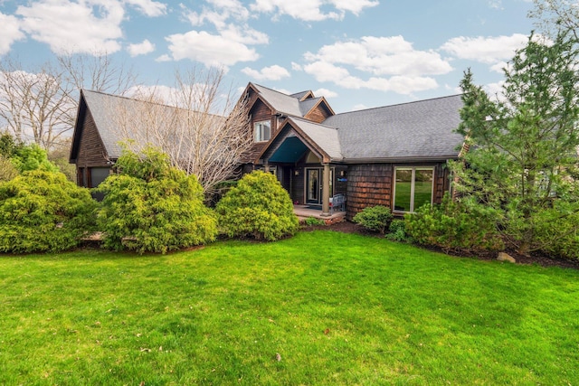 view of front of home with a front lawn, roof with shingles, and a garage