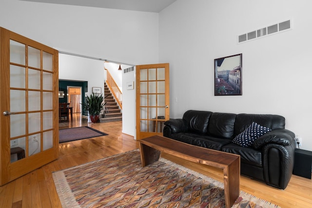 living room with french doors, wood finished floors, stairway, and a high ceiling