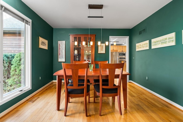dining room with light wood-style floors, plenty of natural light, and baseboards