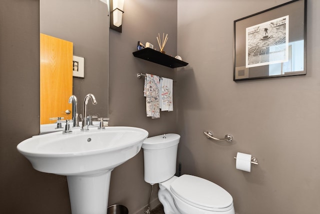 half bath featuring toilet and baseboards