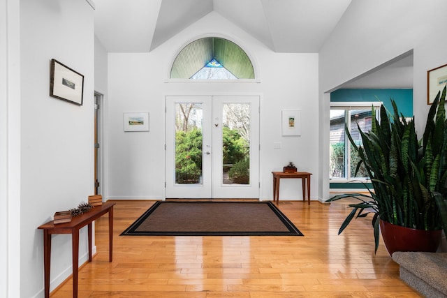 foyer entrance with wood finished floors, vaulted ceiling, and french doors