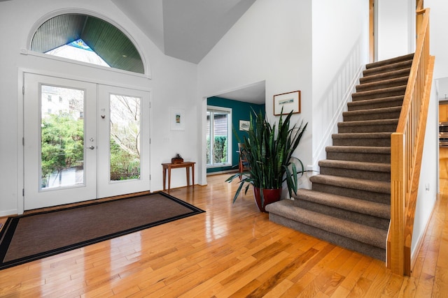 entryway featuring stairs, light wood finished floors, and high vaulted ceiling