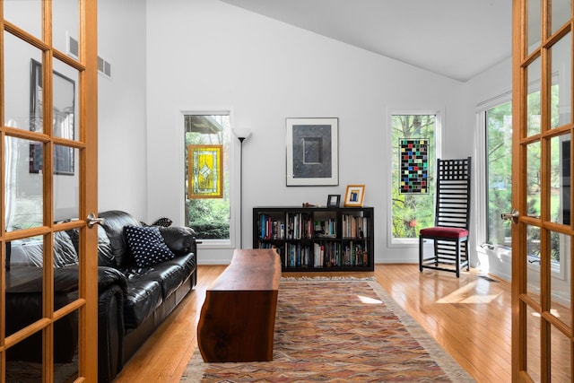 living room featuring hardwood / wood-style floors, high vaulted ceiling, french doors, and baseboards